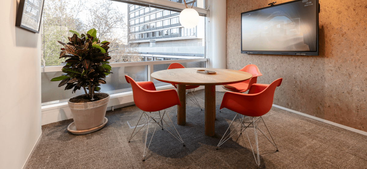 ronde houten tafel met oranje stoelen in vergaderruimte hvk stevens