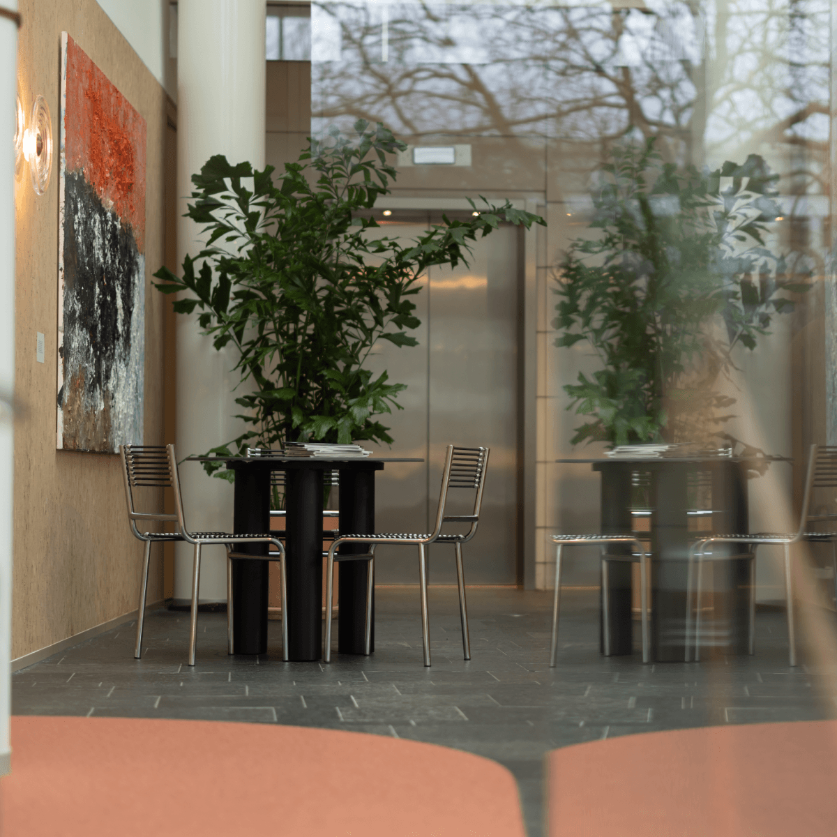 tafel met metalen stoelen naast planten en kunstwerk hvk stevens