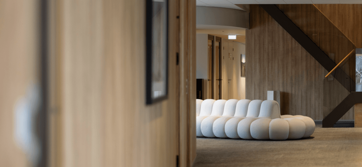 Witte designbank in moderne kantoorhal met trap HVK Stevens