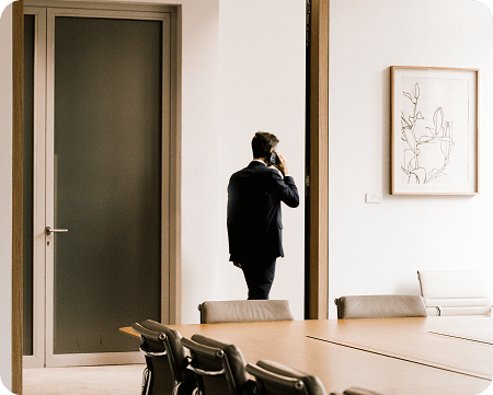 Zakenman voert telefoongesprek terwijl hij bij een vergaderruimte staat