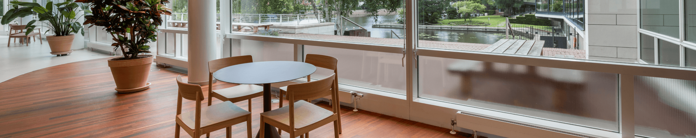 Kleine ronde tafel met houten stoelen naast groot raam met uitzicht op water HVK Stevens