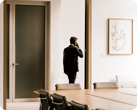 Zakenman voert telefoongesprek terwijl hij bij een vergaderruimte staat