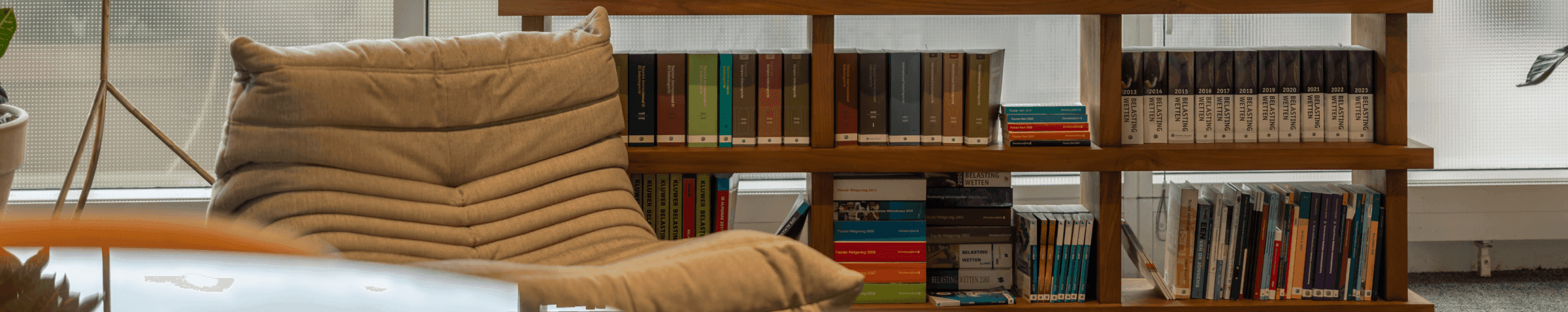 Boekenkast met gekleurde boeken naast comfortabele stoel