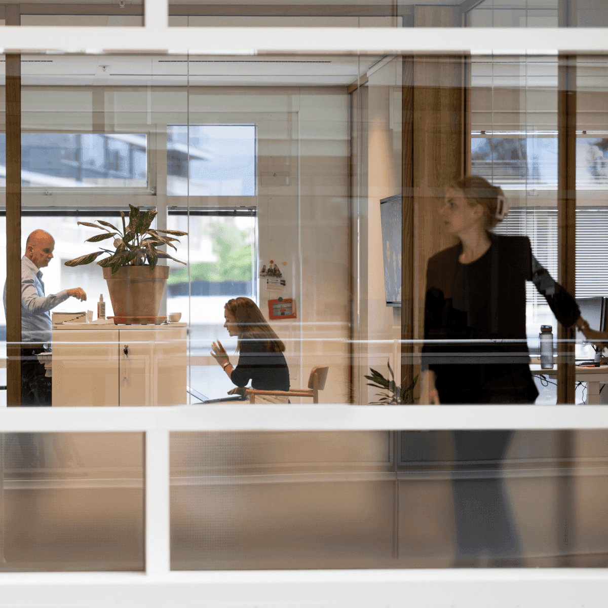 Kantoorinterieur met collega’s in overleg door glaswand