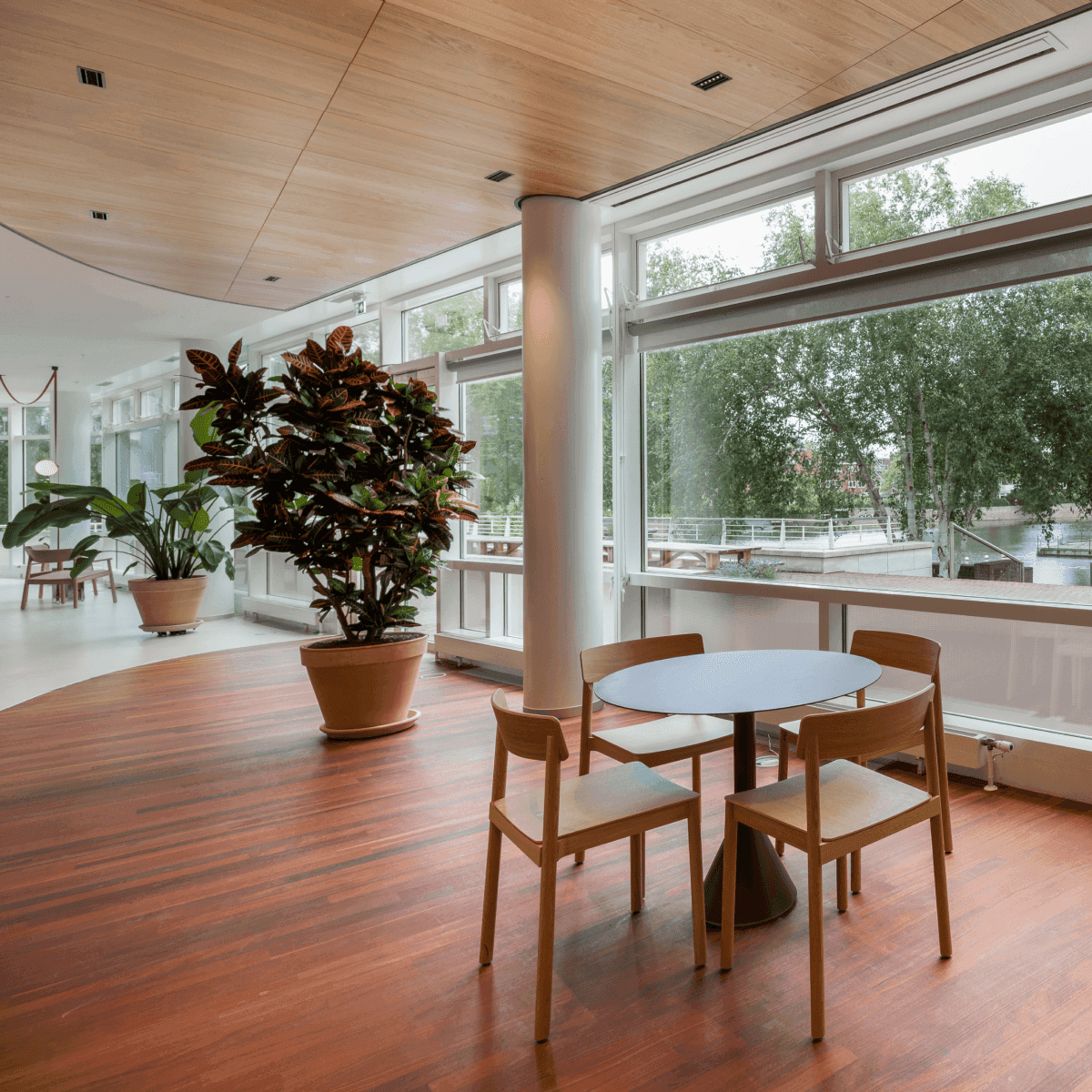 Kleine ronde tafel met houten stoelen naast groot raam met uitzicht op water