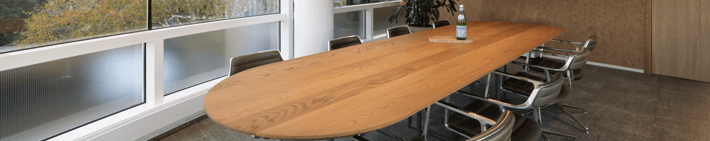 Lange houten vergadertafel met stoelen en scherm
