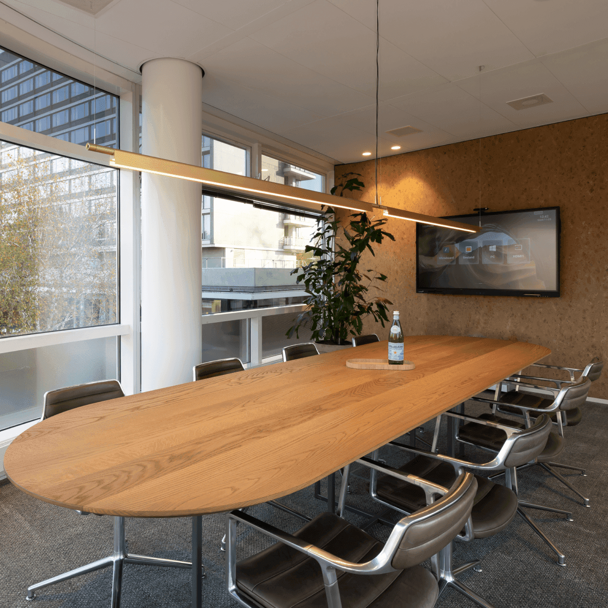Long wooden meeting table with chairs and screen