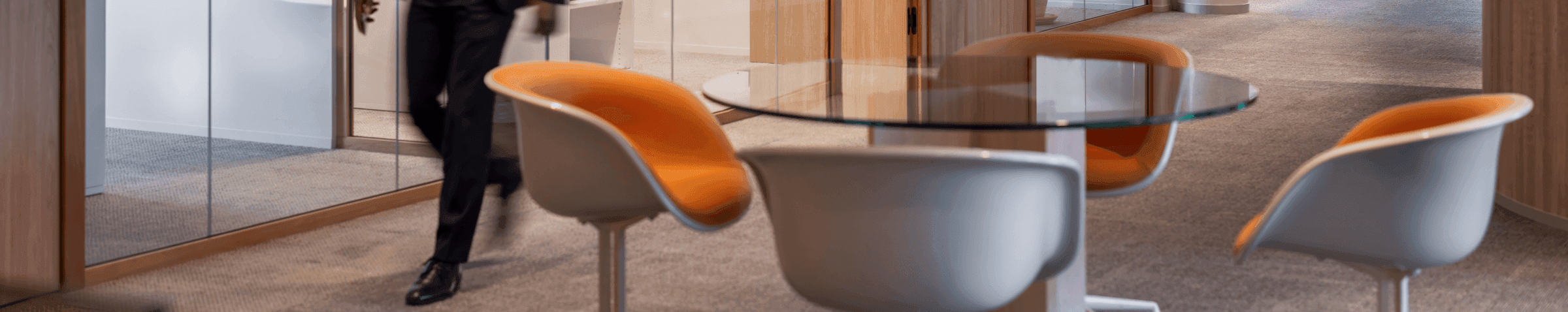 Man in pak loopt langs vergaderruimtes met glazen wanden