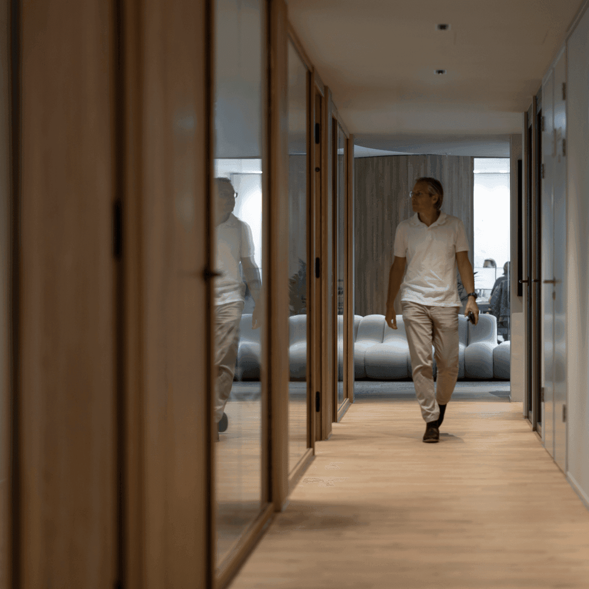 Man walking through hallway with wooden doors and office rooms