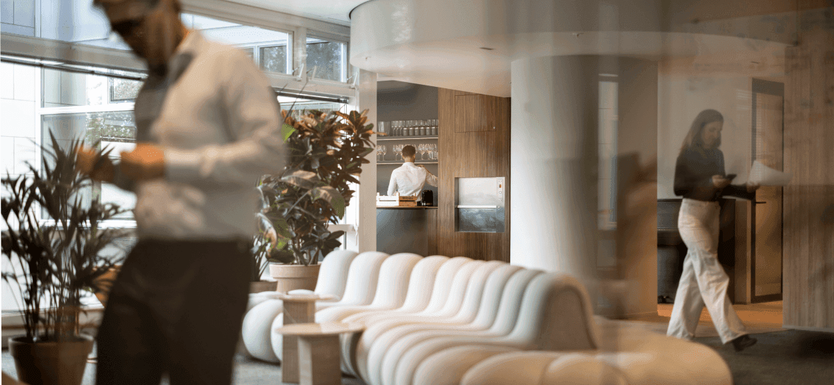 Modern lounge area with white sofa and colleagues in background