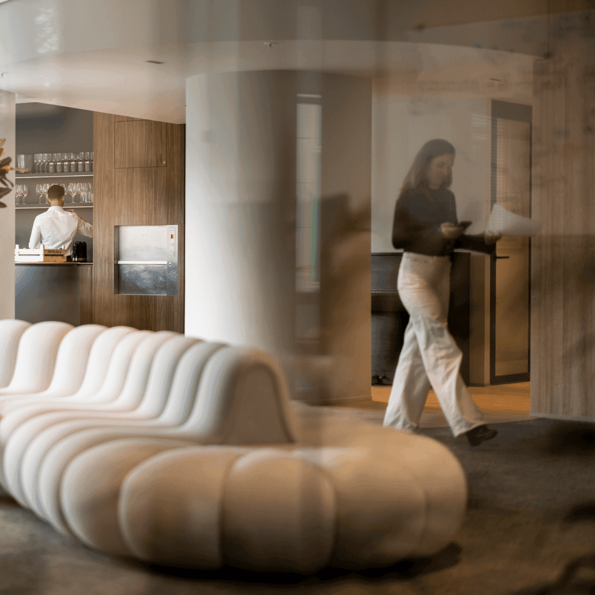 Modern lounge area with white sofa and colleagues in background