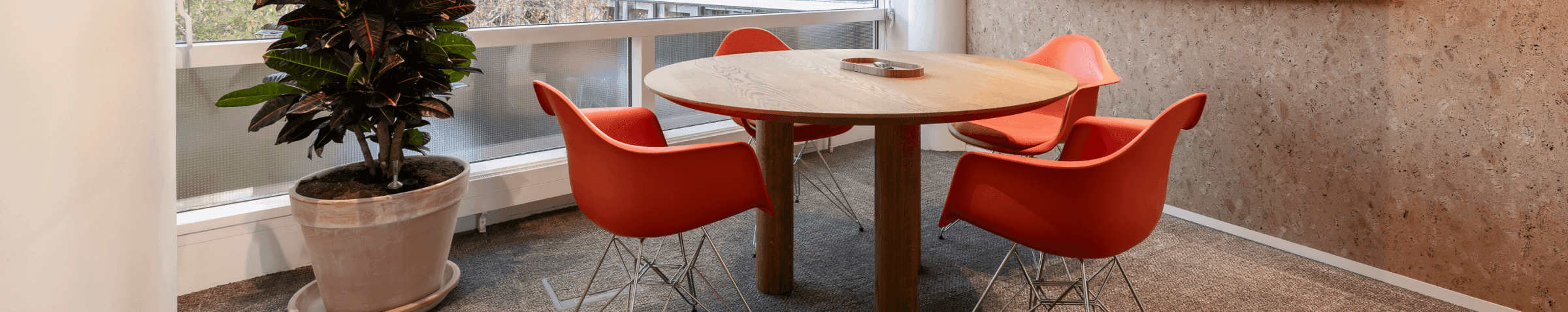 Round wooden table with orange chairs in meeting room