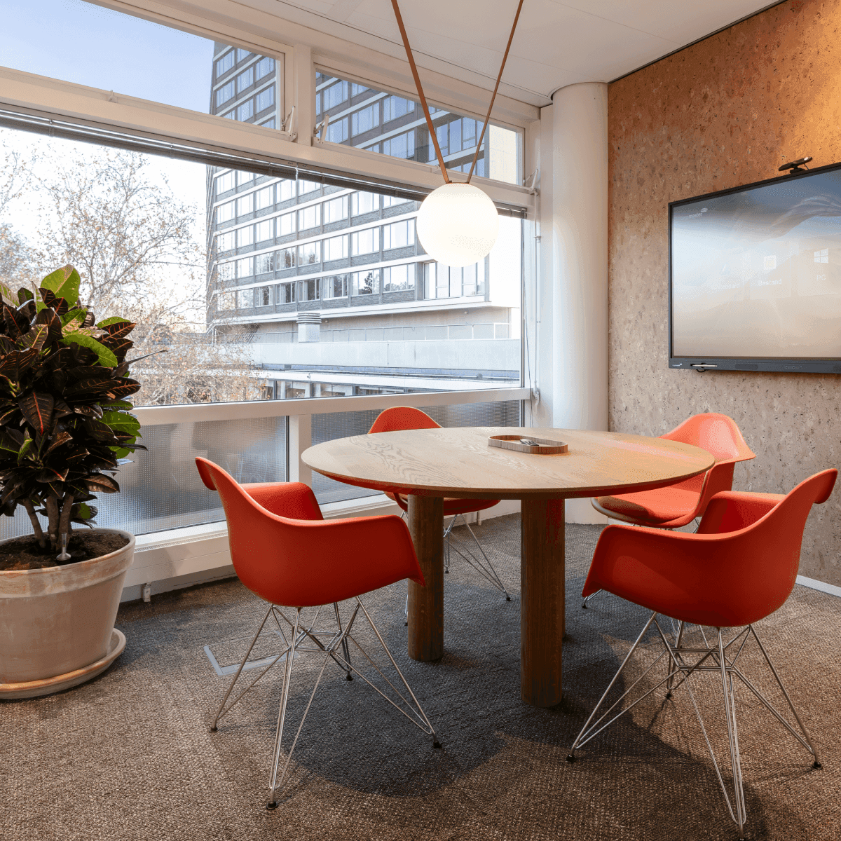 Round wooden table with orange chairs in meeting room