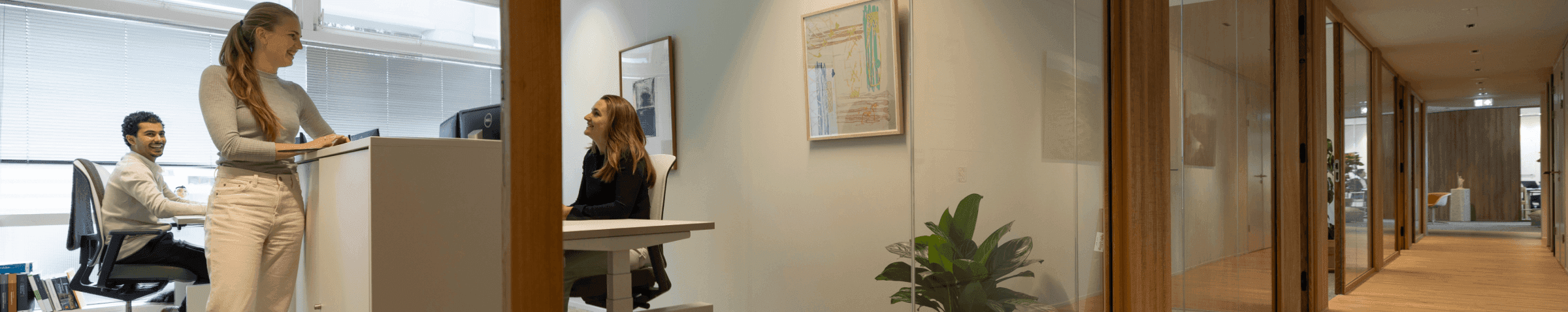 Three colleagues smiling and discussing in bright office space