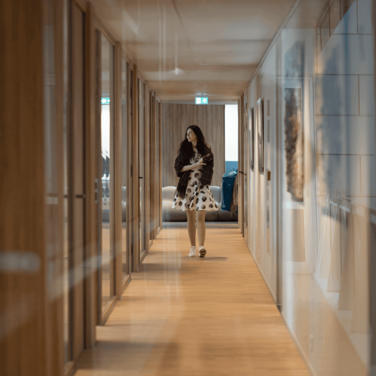 Woman with notepad walking through office hallway with wooden floor