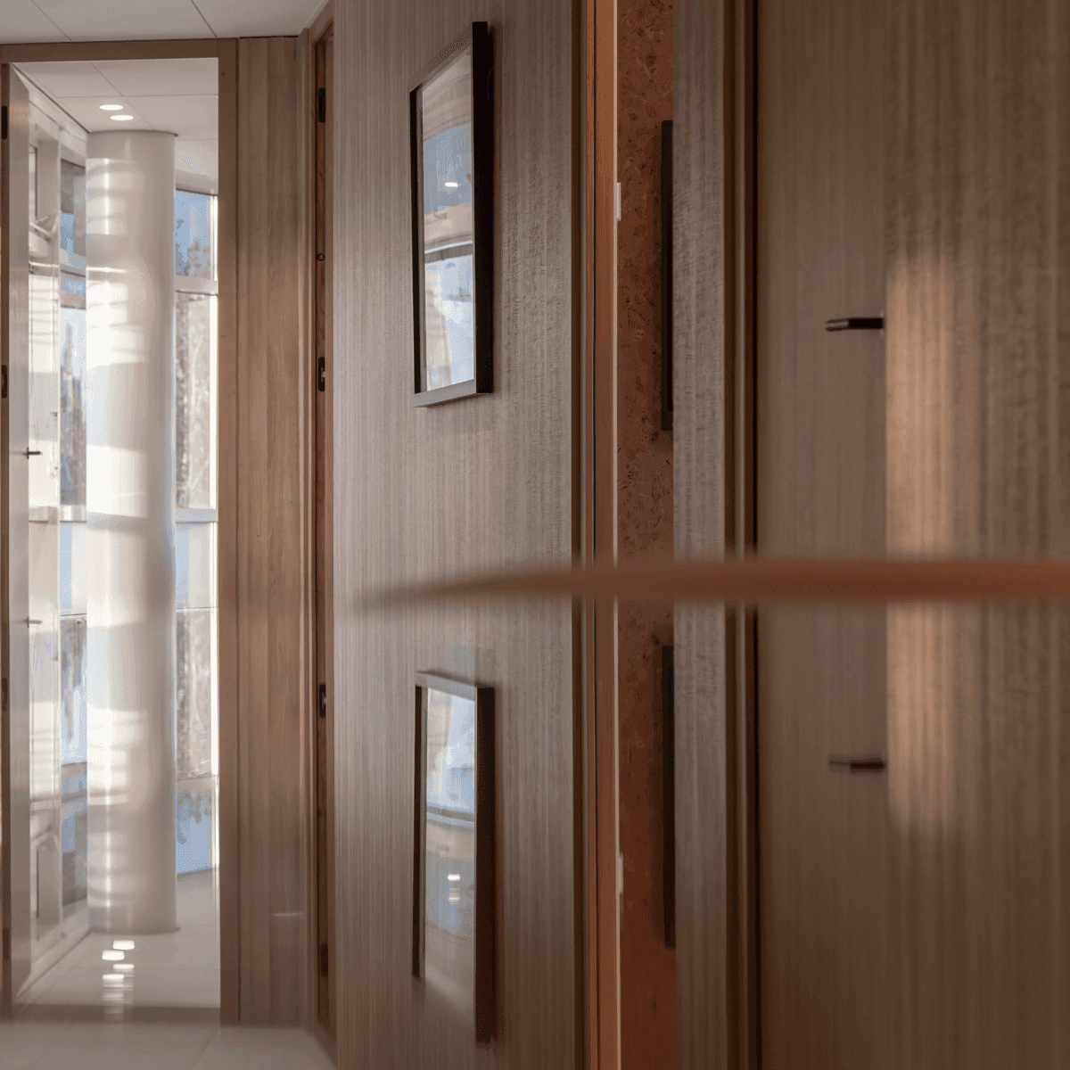 Wooden hallway with reflective surfaces and framed artworks