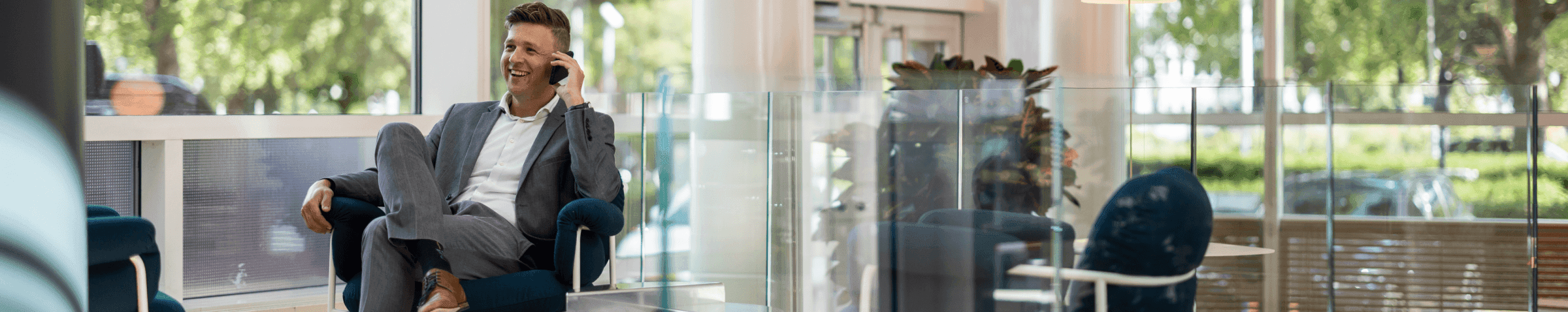 Zakenman in grijs pak telefoongesprek in moderne loungehoek